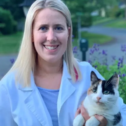 Dr. Bridget Barnes of Northampton Veterinary Clinic standing in front of a pathway, while holding a cat